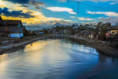 River amidst buildings in town at sunset