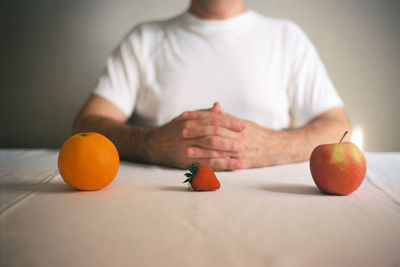 Midsection of man having fruits at table