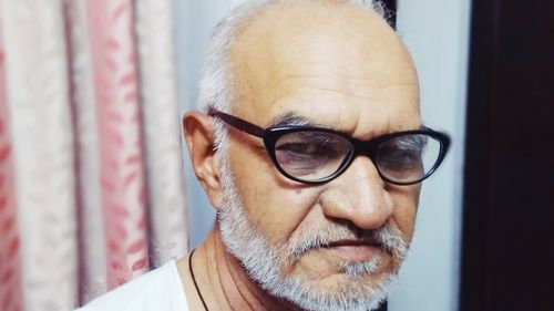 Close-up portrait of man wearing eyeglasses at home