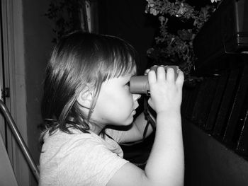Side view of girl looking through binoculars at night