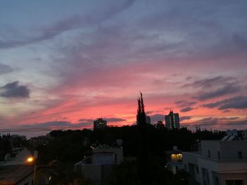 Cityscape against dramatic sky during sunset