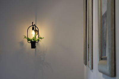 Illuminated electric lamp hanging on wall at home