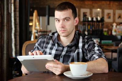 Portrait of young man sitting at restaurant table