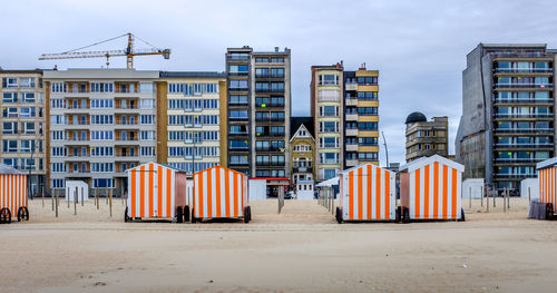 Row of colorful beach cabins against buildings in de panne, belgium