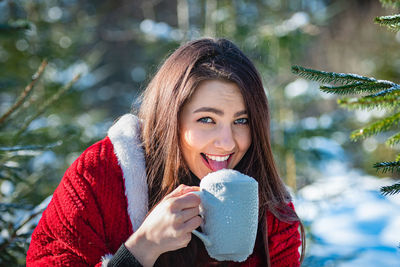 Portrait of smiling young woman holding umbrella during winter