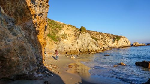 Scenic view of sea by cliff against clear sky