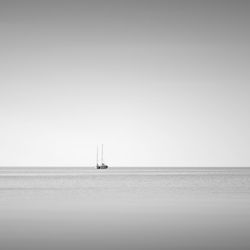 Sailboat sailing on sea against clear sky