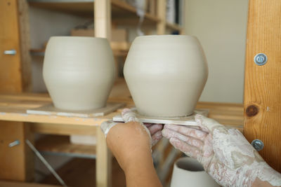 Cropped hands of potter placing ceramic on shelf