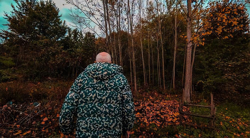 Rear view of man standing on field in forest