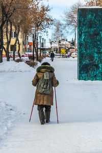 Rear view of woman walking on snow covered landscape