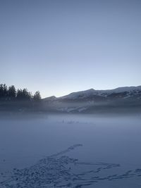 Scenic view of lake by snowcapped mountains against sky