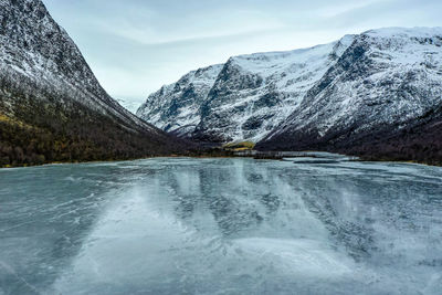 Scenic view of ice covered water and mountains against sky