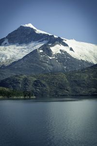 Scenic view of lake by snowcapped mountains against sky