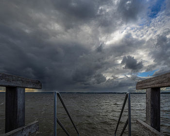 Pier on sea against cloudy sky