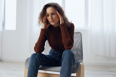 Young woman sitting on sofa at home