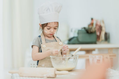 Midsection of baby girl in bowl on table at home