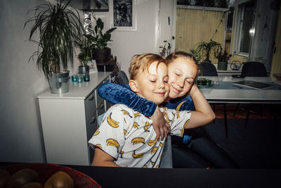 Smiling girl embracing brother in living room