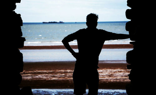 Silhouette people standing on beach against sky