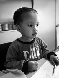 Portrait of boy sitting on table at home