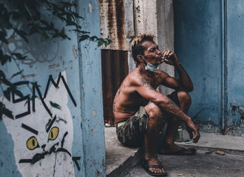 Portrait of young man sitting on wall