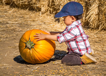 Full length of a boy sitting on pumpkin during halloween