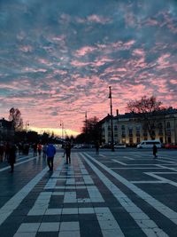 People crossing road against sky during sunset