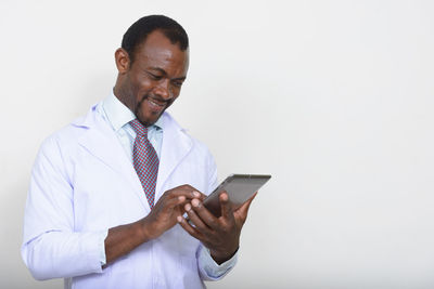 Smiling doctor using digital tablet against white background