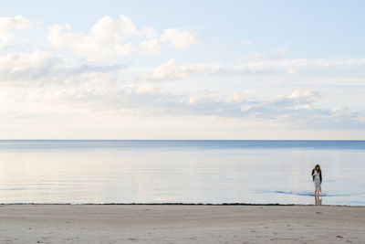 Rear view of man standing on beach against sky