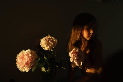 Girl with a flower bouquet against black background