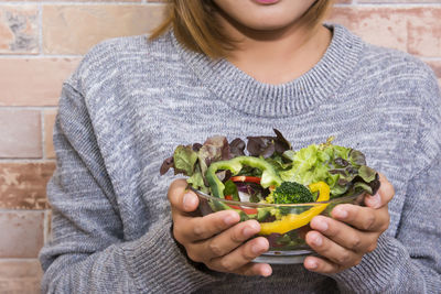 Midsection of woman holding salad in bowl