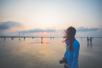 Side view of woman standing at beach against sky