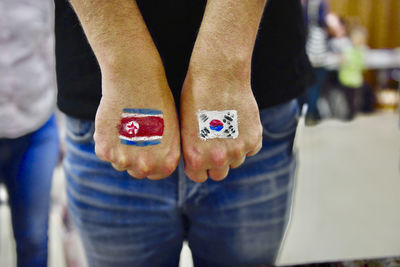 Low section of man standing on floor with painted flags of south and north korea