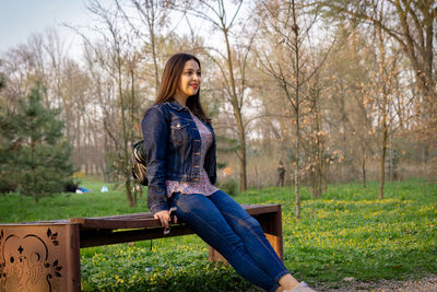 Smiling young woman looking away while sitting in park