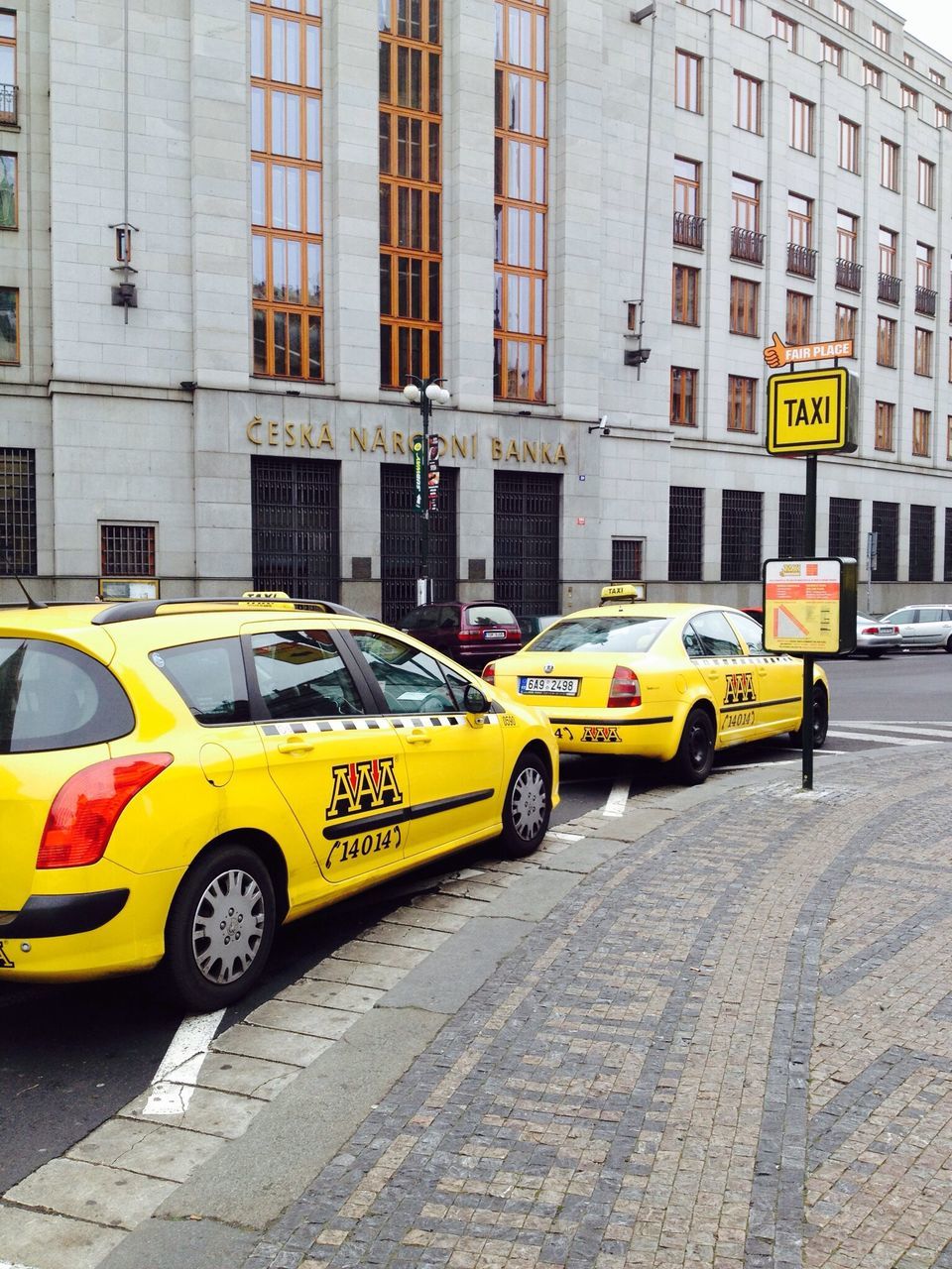 transportation, mode of transport, land vehicle, yellow, building exterior, architecture, built structure, car, city, street, public transportation, road marking, road, travel, city life, on the move, text, stationary, parking, city street