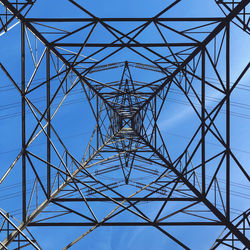 Low angle view of electricity pylon against clear blue sky