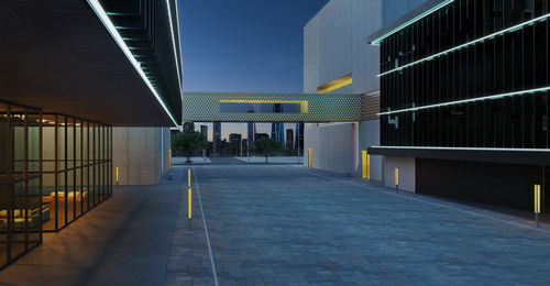 Empty footpath amidst buildings against sky at dusk