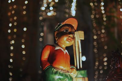 Close-up of figurine against illuminated lighting equipment