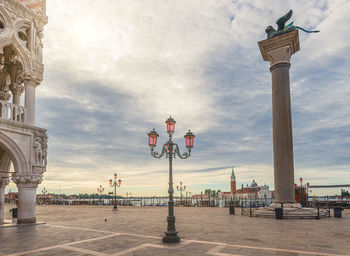 Statue in city against cloudy sky