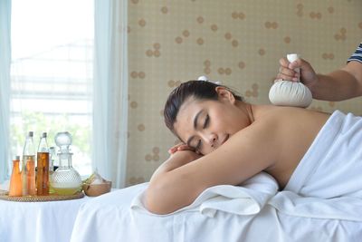 Woman lying down on bed by window