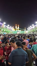 Rear view of people enjoying music concert against sky at night