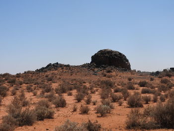 Rock formations on landscape against clear blue sky