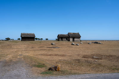 Built structure on field against clear blue sky