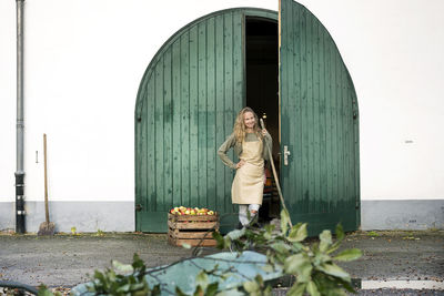 Smiling woman on a farm standing at crate with apples