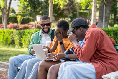 Friends using laptop at park