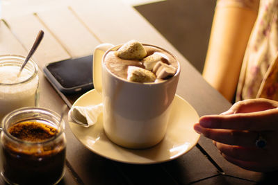 Close-up of hand holding coffee cup on table