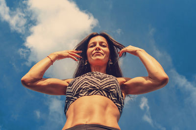 Low angle portrait of woman standing against sky