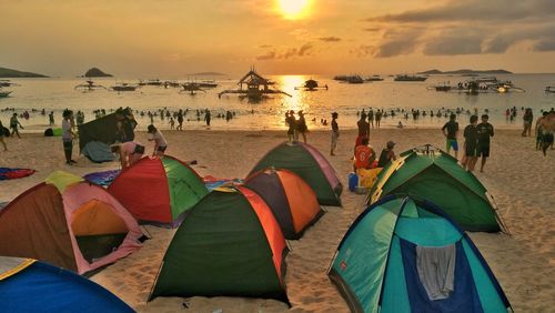 People at beach against sky during sunset