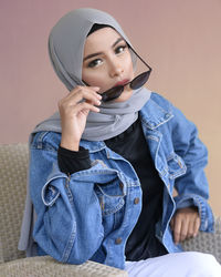 Fashionable young woman wearing hijab against wall
