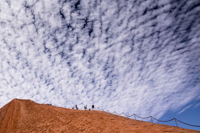 Low angle view of people walking on land against sky