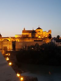 Illuminated buildings against clear sky at dusk